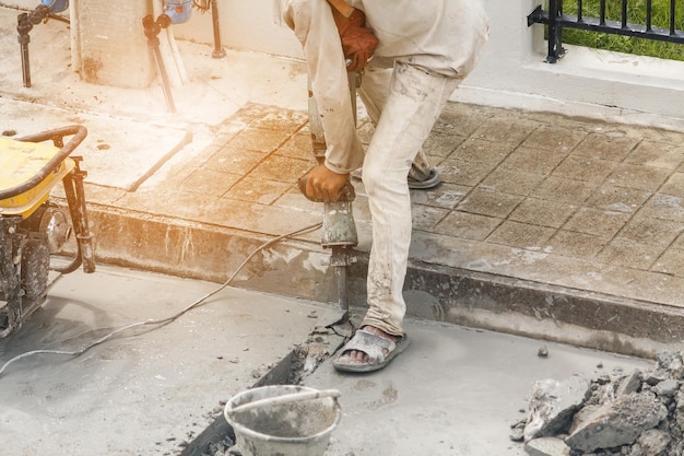 Trabalhador da construção civil usando britadeira perfurando superfície de concreto