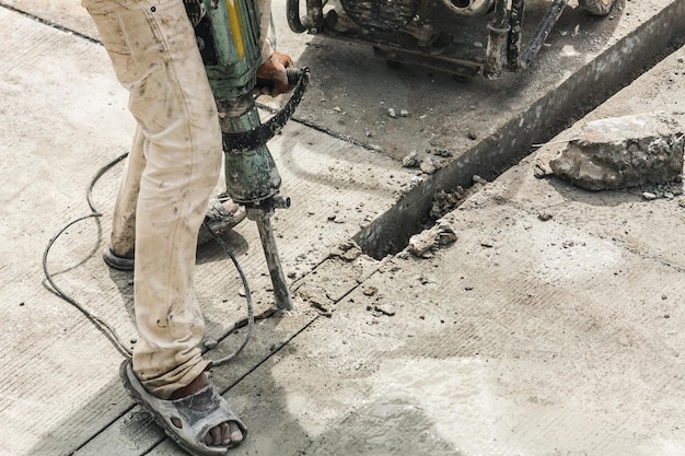 Trabalhador da construção civil usando britadeira perfurando superfície de concreto