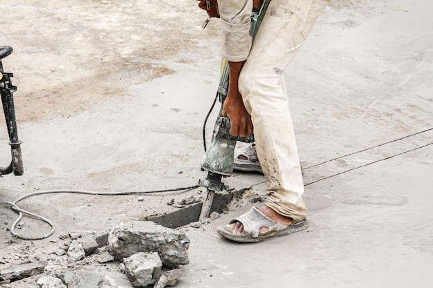 Trabalhador da construção civil usando britadeira perfurando superfície de concreto