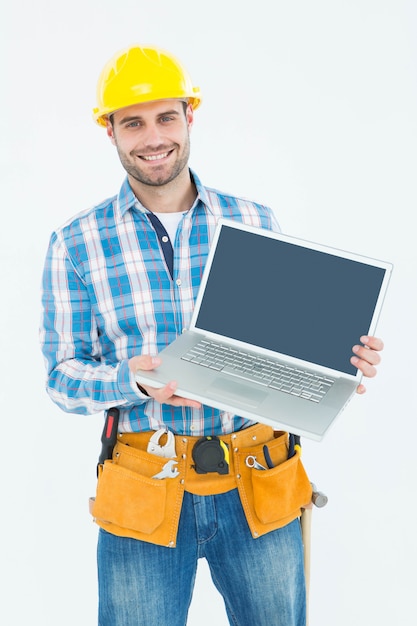 Trabalhador da construção feliz que mostra o laptop