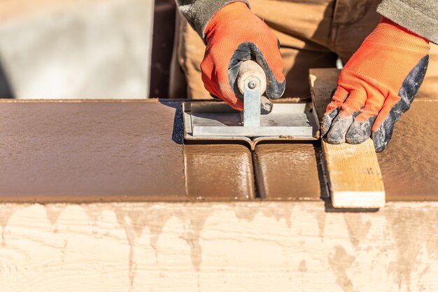 Trabalhador da construção usando um escavadeiro à mão em cimento molhado, moldando em torno de uma nova piscina