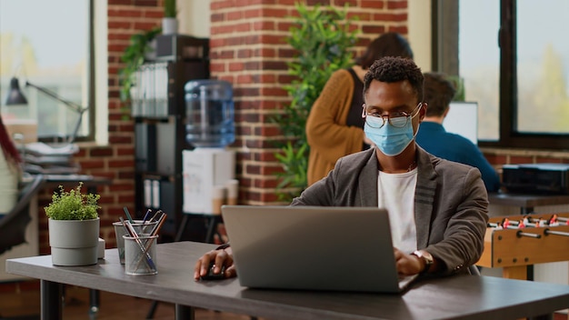 Trabalhador da empresa planejando pesquisa de dados com relatórios de gráficos on-line no laptop no escritório de inicialização, trabalhando no projeto durante a pandemia de coronavírus. homem de negócios no trabalho corporativo. tiro de mão.