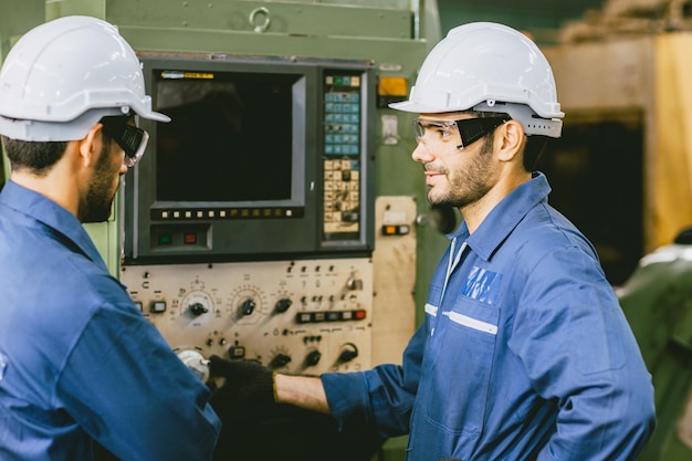 Trabalhador da equipe de engenheiros experientes trabalhando juntos na fábrica de metal operar a máquina CNC de configuração