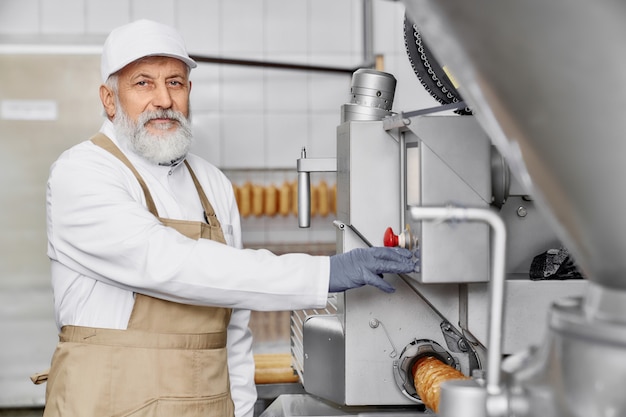 Trabalhador da fábrica de carne posando perto de equipamentos modernos.