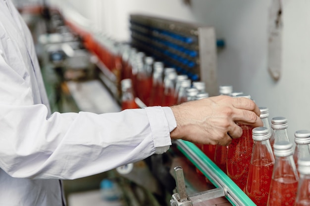 Trabalhador da indústria de alimentos e bebidas trabalhando na máquina da linha de produção de correia transportadora em fábrica de bebidas com área limpa e higiênica