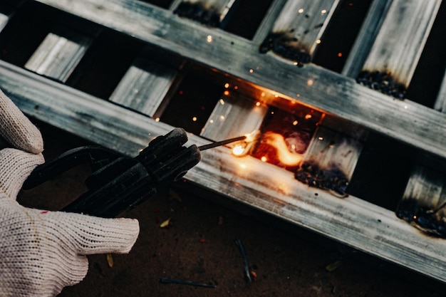 Foto trabalhador da indústria vestindo luva branca e ferro de soldagem no trabalho ao ar livre ferramenta manual de close-up para soldagem de aço conceito industrial usando máquina de soldagem para construção