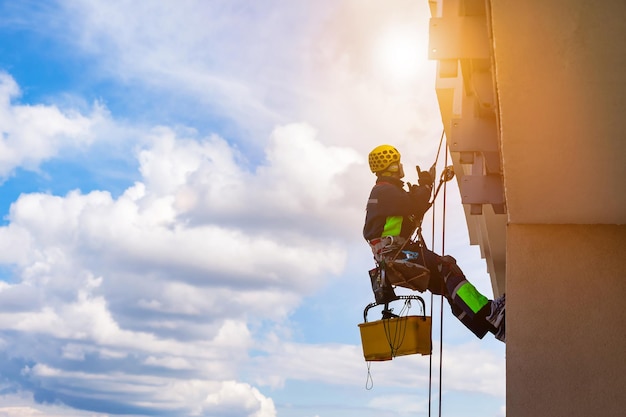 Trabalhador de alpinismo industrial em uniforme lavando vidros exteriores