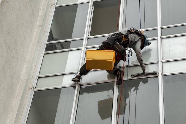 Trabalhador de alpinismo industrial paira sobre fachada residencial