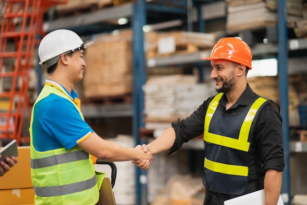 Trabalhador de armazém industrial ou engenheiro em aperto de mão de suíte de segurança celebram o compromisso bem-sucedido ou negociam Cadeia de suprimentos de logística e negócios de armazém Unidade de trabalho em equipe sob o conceito de visão