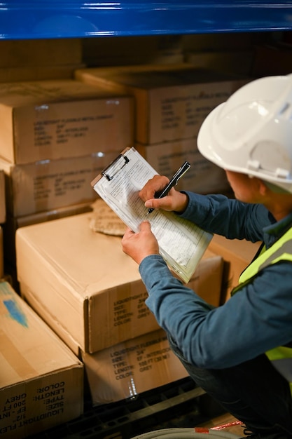 Trabalhador de armazém masculino asiático verificando uma lista de inventário em papel trabalhando no armazém