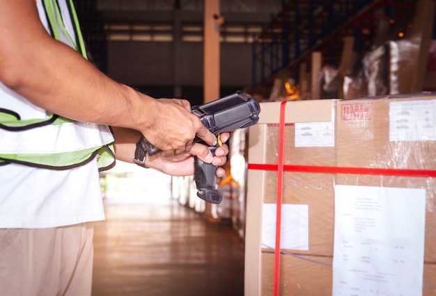 Trabalhador de armazém segurando scanner de código de barras, verificando os produtos. Ferramentas informáticas para gestão de inventário de armazém