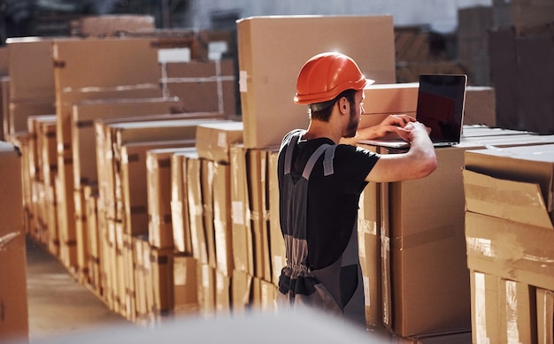 Trabalhador de armazenamento de uniforme e bloco de notas nas mãos verifica a produção.