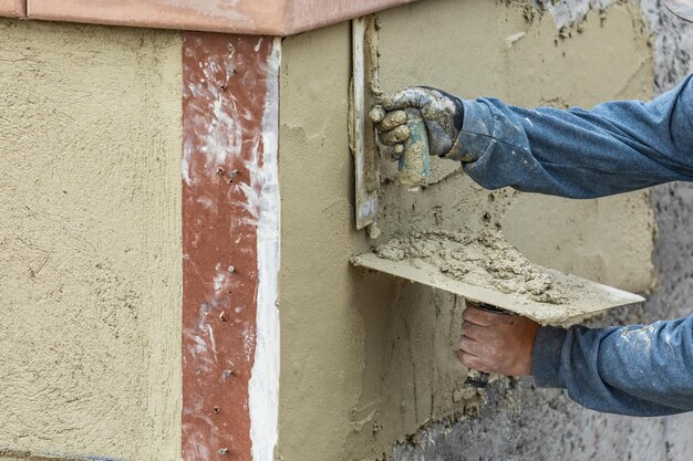 Trabalhador de azulejo aplicando cimento com espátula no canteiro de obras de piscina