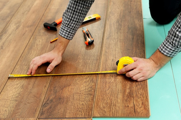 Trabalhador de carpinteiro instalando piso laminado na sala