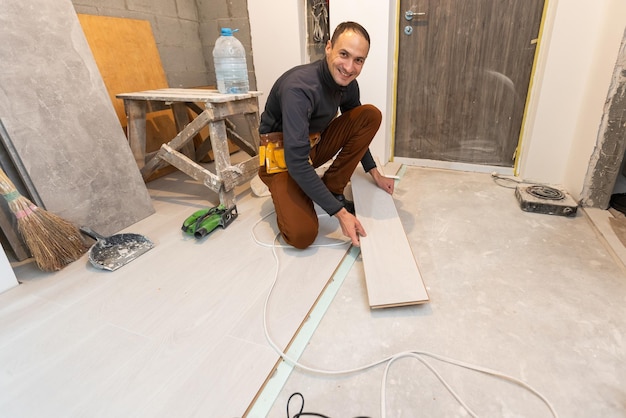 Trabalhador de carpinteiro instalando piso laminado na sala.