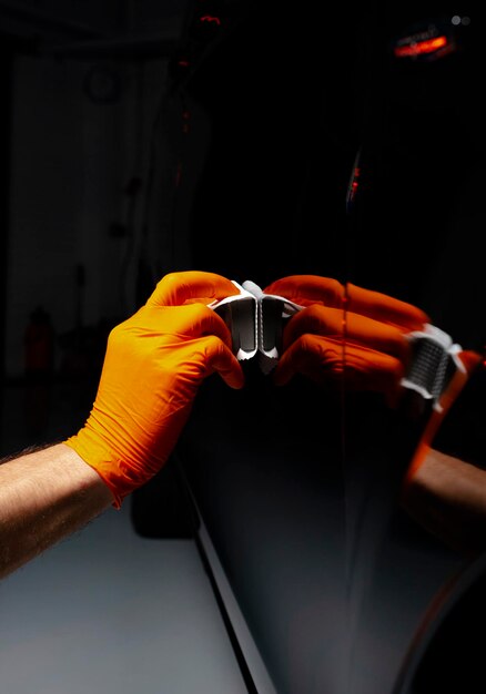 Foto trabalhador de cera de polimento de carros mãos polimento de automóveis buffing e polimento de veículos com cerâmica detalhe de automóveis homem segura um polidor na mão e polimos o carro com nano cerâmica ferramentas para polimento