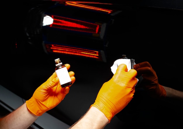 Foto trabalhador de cera de polimento de carros mãos polimento de automóveis buffing e polimento de veículos com cerâmica detalhe de automóveis homem segura um polidor na mão e polimos o carro com nano cerâmica ferramentas para polimento