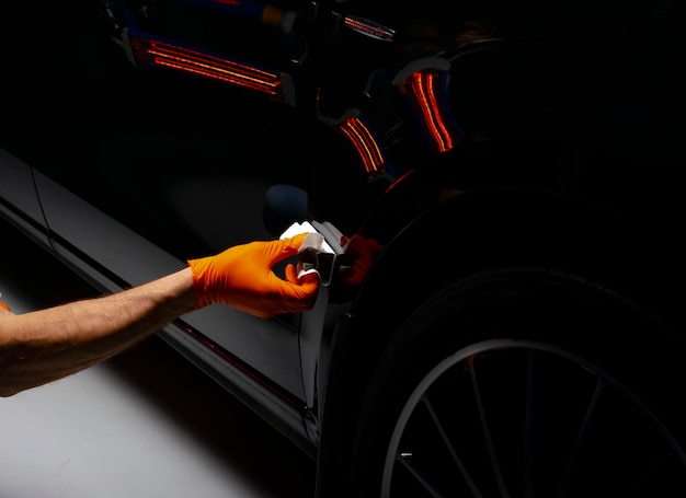 Foto trabalhador de cera de polimento de carros mãos polimento de automóveis buffing e polimento de veículos com cerâmica detalhe de automóveis homem segura um polidor na mão e polimos o carro com nano cerâmica ferramentas para polimento