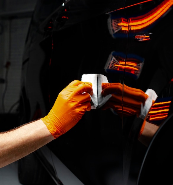 Trabalhador de cera de polimento de carros mãos polimento de automóveis Buffing e polimento de veículos com cerâmica Detalhe de automóveis Homem segura um polidor na mão e polimos o carro com nano cerâmica Ferramentas para polimento