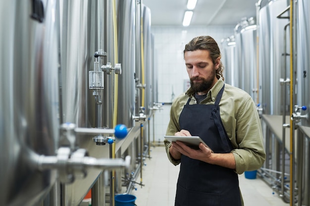 Trabalhador de cervejaria verificando equipamentos