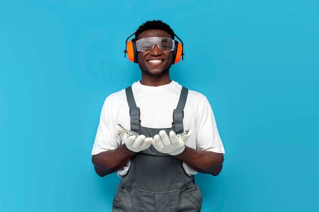 Trabalhador de construção afro-americano em uniforme de mãos dadas em frente a ele em fundo azul