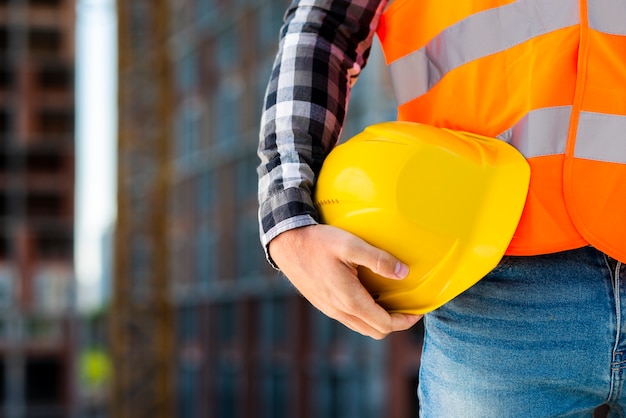 Foto trabalhador de construção de close-up segurando o capacete