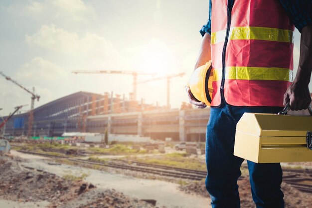 Trabalhador de construção ou técnico segurando caixa de ferramentas e capacete no fundo do local de trabalho de borracha suave pronto para reparar e corrigir o conceito