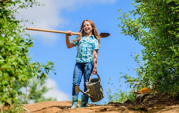 Trabalhador de criança de jardinagem ensolarado ao ar livre família ligação primavera lado do campo vila futuro sucesso menina no rancho verão agricultura agricultor menina ferramentas de jardim pá e regador