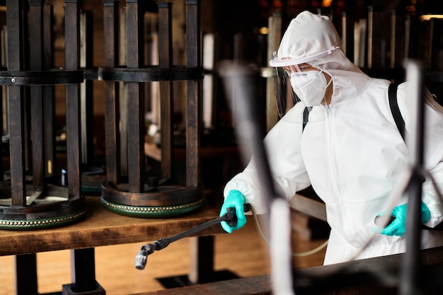 Foto trabalhador de desinfecção em traje de proteção pulverizando café contaminado devido à epidemia de coronavírus