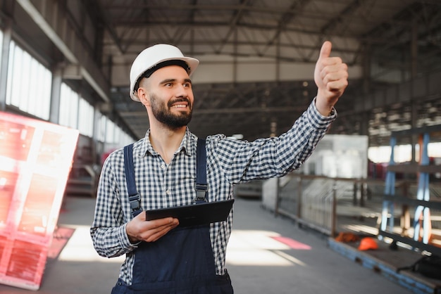 Trabalhador de engenheiro da indústria pesada profissional feliz usando uniforme e capacete em uma fábrica de aço Especialista industrial sorridente em pé em uma fabricação de construção de metal