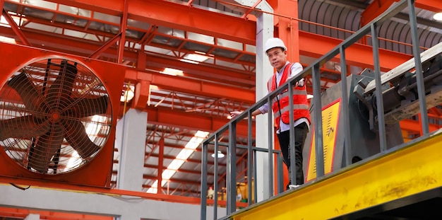 Trabalhador de engenheiro de fábrica de retrato operando máquina de telhado de folha de metal na indústria pesada Trabalhador de fábrica em capacete de segurança nas instalações industriais da fábrica