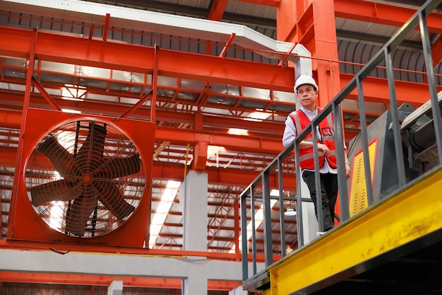 Trabalhador de engenheiro de fábrica de retrato operando máquina de telhado de folha de metal na indústria pesada Trabalhador de fábrica em capacete de segurança nas instalações industriais da fábrica