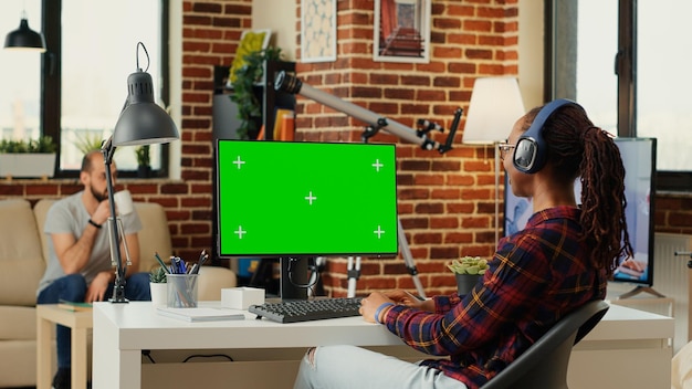 Trabalhador de escritório analisando o modelo de tela verde no monitor, trabalhando com fundo simulado isolado na mesa. Usando a exibição de chroma key em branco com espaço de cópia no computador pessoal em casa.