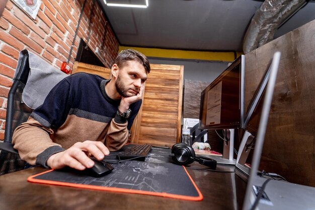 Trabalhador de escritório atento está sentado em sua mesa e olhando para o monitor. Interior moderno do escritório. Conceito de negócios