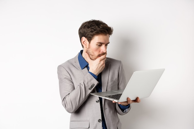 Trabalhador de escritório chocado de terno olhando preocupado para a tela do laptop, tendo problemas no trabalho