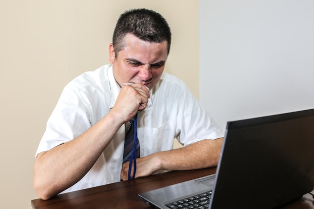 Trabalhador de escritório comendo seu distintivo. burnout ocupacional. condições de trabalho ruins. gerente infeliz com laptop. calor de verão. cumprimento de prazos. trabalho estressante na mesa. homem desesperado.