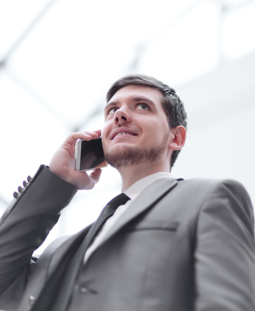 Trabalhador de escritório ouvindo seu interlocutor de telefone com concentração enquanto está na janela do escritório