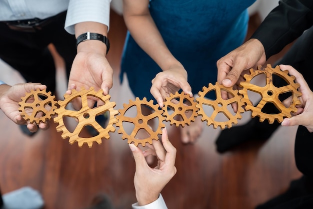 Trabalhador de escritório segurando a roda dentada como unidade e trabalho em equipe no conceito de local de trabalho corporativo Diversos colegas de negócios mostrando símbolo de sistema visionário e mecanismo para o sucesso empresarial Concord