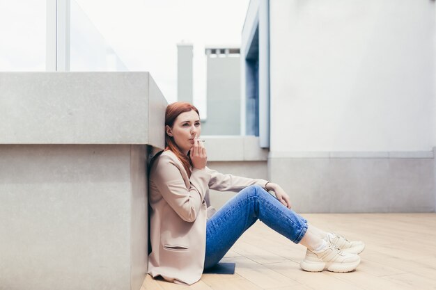 Trabalhador de escritório triste sentada no chão da varanda de um escritório moderno