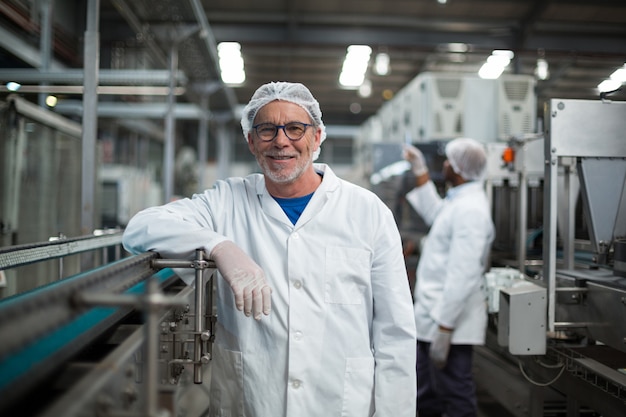 Trabalhador de fábrica sorridente ao lado de linha de produção