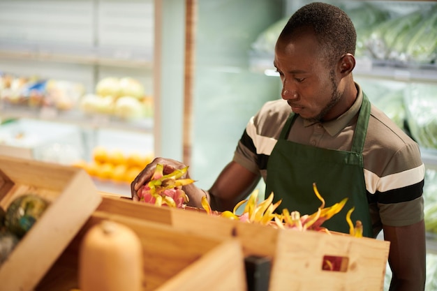 Trabalhador de loja distribuindo frutas do dragão