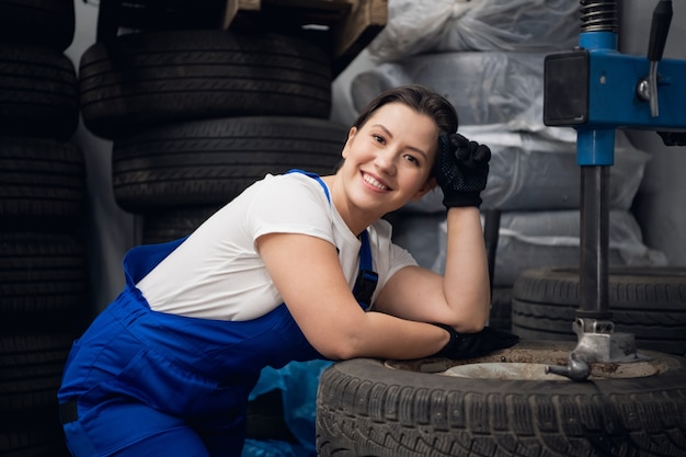 Foto trabalhador de manutenção de automóveis posando ao lado de rodas e uma máquina-ferramenta