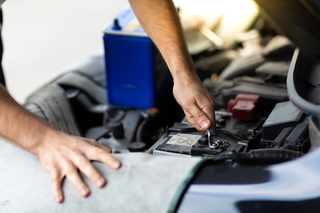 Trabalhador de mecânico de automóveis verificando e trocando a bateria do carro. Manutenção do carro e conceito de garagem de serviço automático.