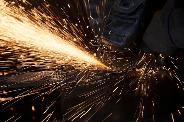 Trabalhador de metal irreconhecível, moendo metal com uma serra elétrica