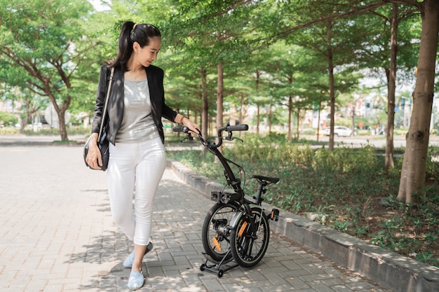 Trabalhador de mulher asiática segurando sua bicicleta dobrável