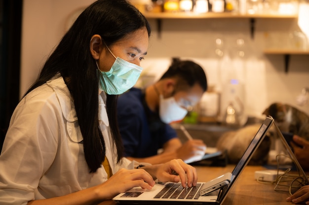 Trabalhador de negócios de designer criativo, trabalhando em espaço espaçado e usando uma máscara médica Para impedir a propagação do coronavírus COVID-2019, Escritório doméstico para pequenos grupos de trabalho em casa