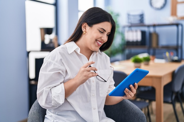 Trabalhador de negócios jovem hispânica usando touchpad trabalhando no escritório