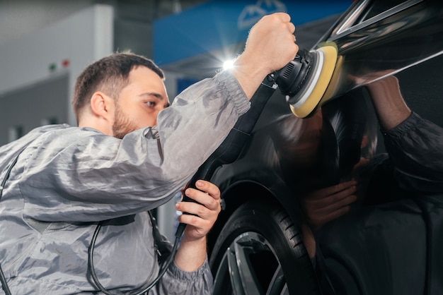 Trabalhador de polimento de carro com lixadeira especial e cera a partir de arranhões no posto de gasolina