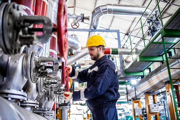 Trabalhador de refinaria em roupas de trabalho de proteção e capacete amarelo trabalhando na indústria petroquímica