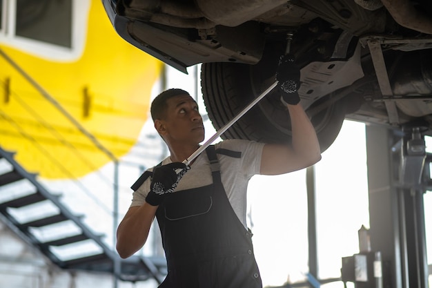 Trabalhador de reparação de automóveis experiente que conserta o automóvel do cliente